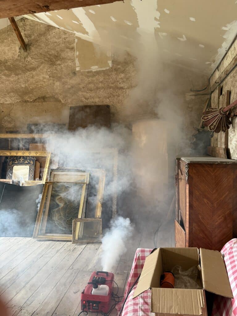 Fumée d'exercice envahissant une pièce du château remplie de cadres dorés et de mobilier ancien